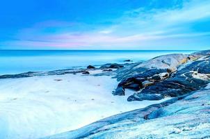 het uitzicht op het zandstrand en de zeegolf met rots en rif op de ochtend? foto