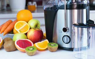 rijp fruit, groenten en een sapcentrifuge voor maken vers sap Aan de tafel in de keuken. maken heerlijk en gezond sappen Bij huis. selectief focus. detailopname. foto