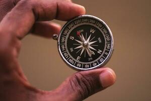 hand- houden kompas - kompas analoog in donker terug grond foto