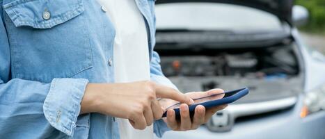 afbreken, gebroken auto, reparatie. vrouw toepassingen mobiel telefoon controleren verzekering premies door toepassing ten gevolge naar auto ongeluk . vind garage naar krijgen auto gemaakt gedurende land tour, aan het wachten voor helpen, noodgeval. foto