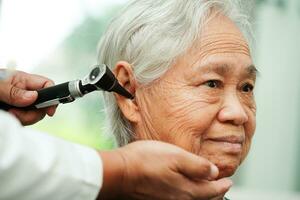 otolaryngoloog of ent arts dokter onderzoeken senior geduldig oor met otoscoop, horen verlies probleem. foto