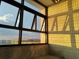 de avond zonlicht scheen door de venster en gips schaduwen Aan de wit betegeld muren. foto
