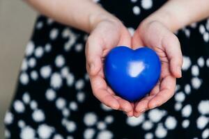 blauw hart in de handen van een vrouw in een polka punt jurk foto