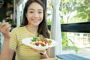 gezond voedsel. mooi vrouw meisje glimlachen genieten eten vers groente salade Aan ontbijt Gezondheid. gelukkig Aziatisch vrouw mooi zo emotie. diëten, ontgiften, eetpatroon, verliezen gewicht, schoon eten, vegetarisch, voedingsdeskundige foto
