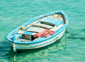 een klein blauw boot drijvend in de Doorzichtig water foto