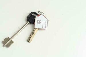 sleutel keten met huis symbool en sleutels Aan wit achtergrond, echt landgoed concept foto