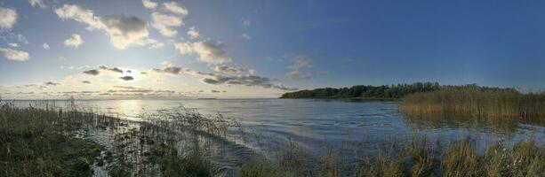 herfst landschap, panorama van de meer, geel droog riet in de voorgrond, instelling zon foto