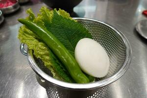 detailopname van vers rauw geassorteerd groenten Leuk vinden sla, kroon madeliefje en groen paprika's Aan een mand, zuiden Korea foto