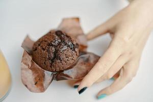 vrouw hand pakt chocolade cupcake van tafel foto