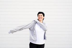 vrouw met een grijze jas die buiten staat op een grijze effen achtergrond foto