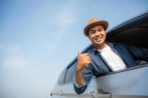 jonge knappe aziatische man die auto rijdt om te reizen foto