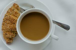 kop van koffie en sesam croissant voor ontbijt foto
