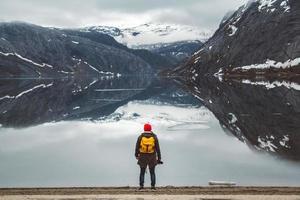 man die op de achtergrond van bergen en meer staat, maakt een foto