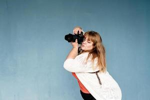 plus size vrouw fotograaf buitenshuis op blauwe effen achtergrond foto