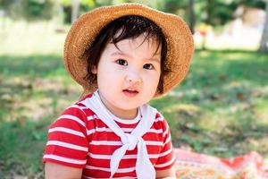 schattige kleine baby in een rode jurk en srtaw hoed op een picknick in het park foto