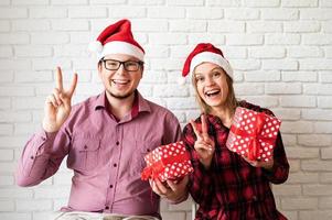 gelukkig Kerstmispaar in santahoeden op witte bakstenen muurachtergrond foto