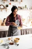 jonge latijnse vrouw die eieren zwaait die in de keuken koken foto