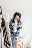 creatieve vrouw met blauw geverfd haar schilderij in haar atelier foto