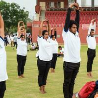 nieuw Delhi, Indië, juni 21, 2023 - groep yoga oefening sessie voor mensen Bij Yamuna sport- complex in Delhi Aan Internationale yoga dag, groot groep van volwassenen Bijwonen yoga klasse in krekel stadion foto