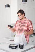 man met een wegwerp plastic zak met voedselbezorging in de keuken foto