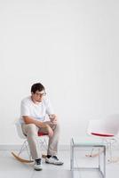 jonge depressieve man met hoofdpijn zittend op de stoel foto