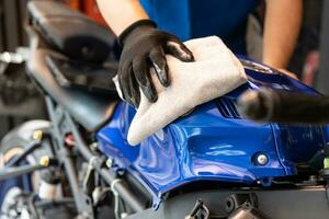Biker man schoonmaak motorfiets, gepolijst en wax coating op brandstoftank bij garage. motorfiets onderhoud en reparatie concept. foto