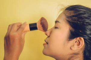 schoonheidsgezicht van aziatische vrouw door borstels op de huid toe te passen door cosmetica. foto