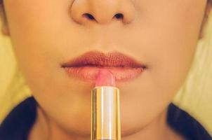 schoonheidsgezicht van de vrouw door lippenstift op de mond toe te passen door cosmetica. foto