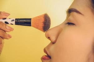 schoonheidsgezicht van aziatische vrouw door borstels op de huid toe te passen door cosmetica. foto