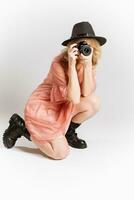portret van een schattig meisje fotograaf in een hoed poseren met een camera in haar handen in de studio Aan een wit achtergrond foto