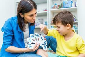 een schattig jongen met een toespraak therapeut is onderwezen naar uitspreken de brieven, woorden en klinkt. foto