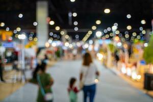 wazig afbeeldingen van handel beurzen in de groot hal. beeld van mensen wandelen Aan een handel eerlijk tentoonstelling of expo waar bedrijf mensen tonen innovatie werkzaamheid en Cadeau producten in een groot hal. foto