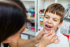 een schattig jongen met een toespraak therapeut is onderwezen naar uitspreken de brieven, woorden en klinkt. foto