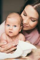 portret van een jong vrouw wie teder geeft voor haar baby foto