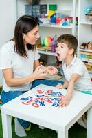 een schattig jongen met een toespraak therapeut is onderwezen naar uitspreken de brieven, woorden en klinkt. foto