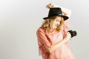 portret van een schattig meisje fotograaf in een hoed poseren met een camera in haar handen in de studio Aan een wit achtergrond foto