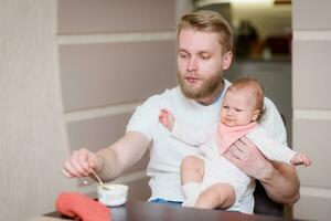 vader feeds zijn ondeugend baby wie weigert naar eten fruit puree foto