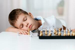 de kind gespeeld schaak en viel in slaap Bij de tafel foto