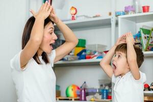 schattig vrouw toespraak therapeut geeft les kind naar uitspreken woorden geluiden en brieven correct in kantoor foto