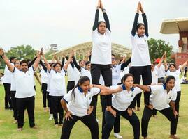 nieuw Delhi, Indië, juni 21, 2023 - groep yoga oefening sessie voor mensen Bij Yamuna sport- complex in Delhi Aan Internationale yoga dag, groot groep van volwassenen Bijwonen yoga klasse in krekel stadion foto