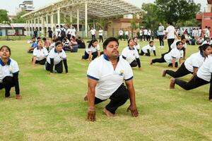 nieuw Delhi, Indië, juni 21, 2023 - groep yoga oefening sessie voor mensen Bij Yamuna sport- complex in Delhi Aan Internationale yoga dag, groot groep van volwassenen Bijwonen yoga klasse in krekel stadion foto