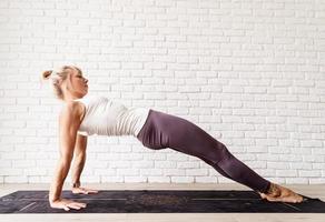 blonde vrouw die thuis yoga beoefent, glute bridge doet
