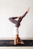 blonde vrouw die thuis yoga beoefent, hoofdstand doet foto