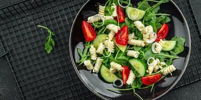 pasta salade fusilli pasta, komkommer, tomaat, groen sla, ui aan het eten voorafje maaltijd voedsel tussendoortje Aan de tafel kopiëren ruimte voedsel achtergrond rustiek top visie foto