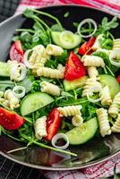 pasta salade fusilli pasta, komkommer, tomaat, groen sla, ui aan het eten voorafje maaltijd voedsel tussendoortje Aan de tafel kopiëren ruimte voedsel achtergrond rustiek top visie foto