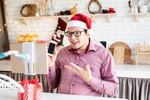 man in kerstmuts begroet zijn vrienden in videochat of bel op tablet foto