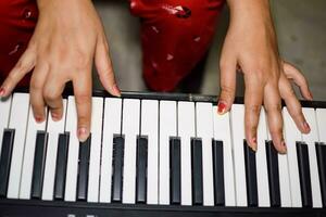 Aziatisch jongen spelen de synthesizer of piano. schattig weinig kind aan het leren hoe naar Speel piano. kind handen Aan de toetsenbord binnen. foto