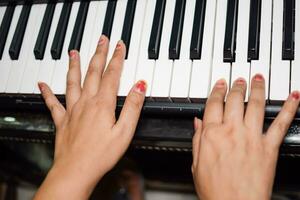 Aziatisch jongen spelen de synthesizer of piano. schattig weinig kind aan het leren hoe naar Speel piano. kind handen Aan de toetsenbord binnen. foto