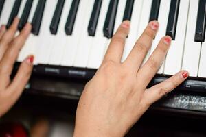 Aziatisch jongen spelen de synthesizer of piano. schattig weinig kind aan het leren hoe naar Speel piano. kind handen Aan de toetsenbord binnen. foto