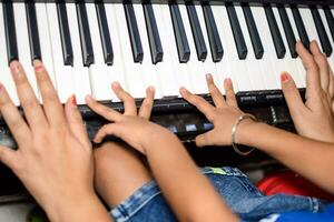 Aziatisch jongen spelen de synthesizer of piano. schattig weinig kind aan het leren hoe naar Speel piano. kind handen Aan de toetsenbord binnen. foto